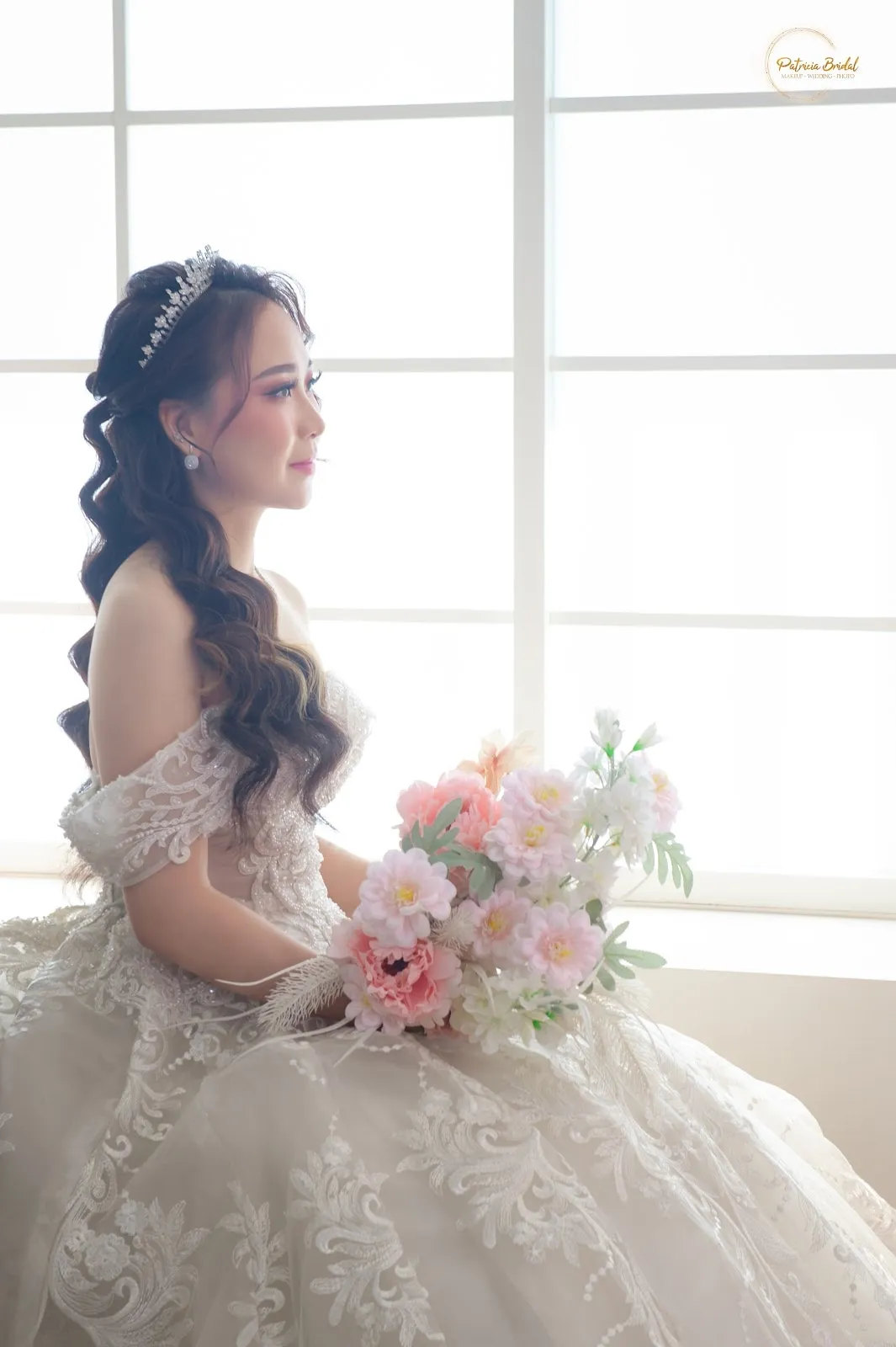 Pengantin duduk memegang buket bunga pastel dengan gaun renda