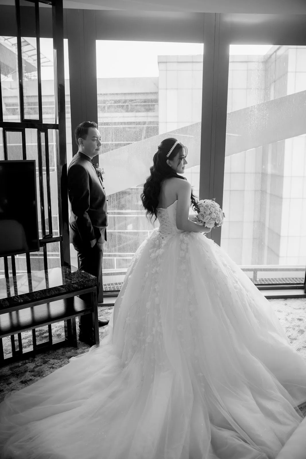 Pengantin dengan ball gown strapless berekor panjang, difoto hitam putih