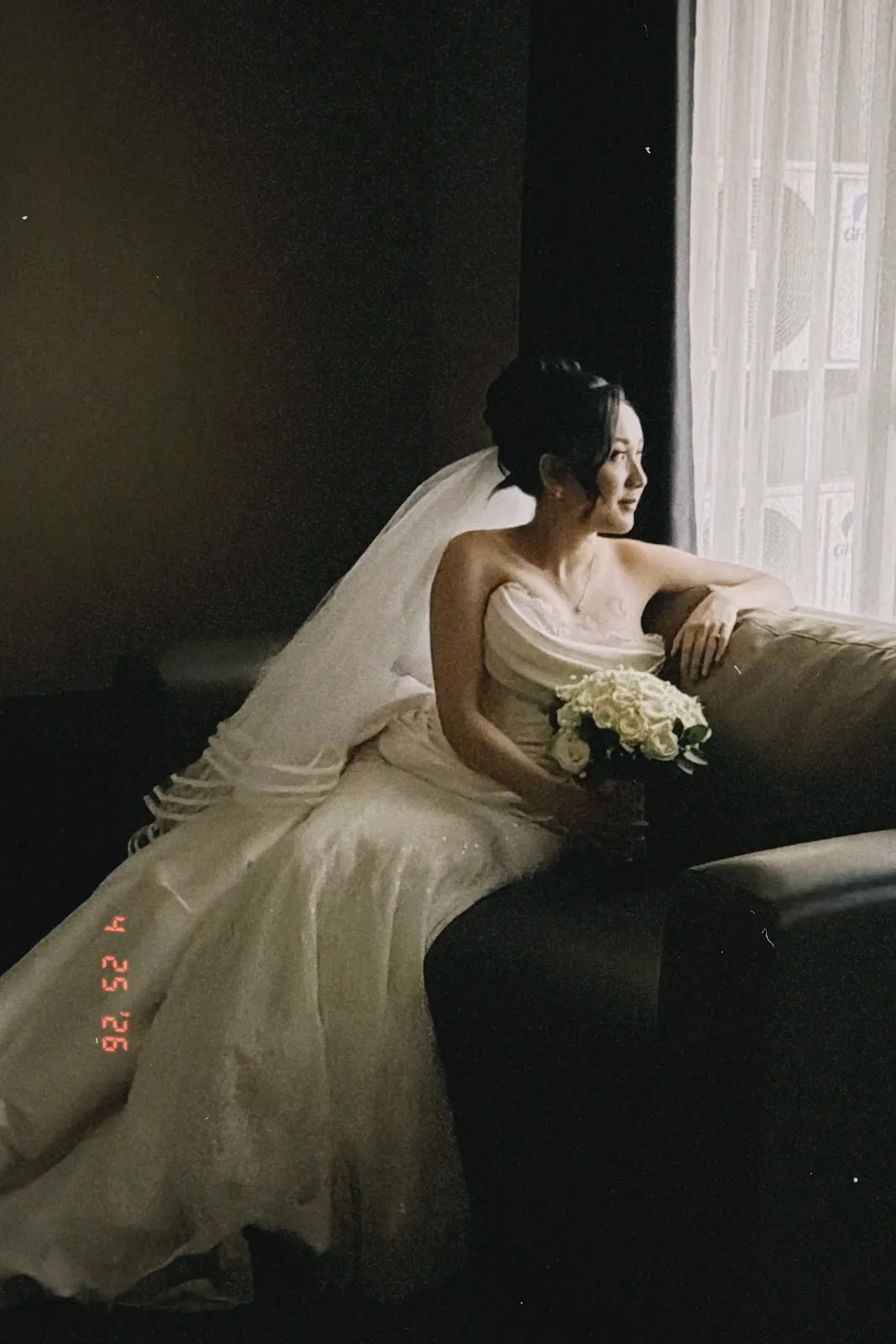 Pengantin dengan gaun satin dan kerudung panjang dalam cahaya temaram