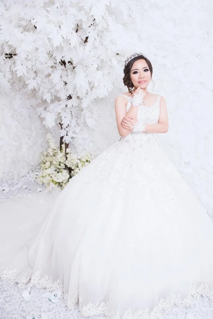 Pengantin dengan ball gown berkilau dan tiara di studio serba putih