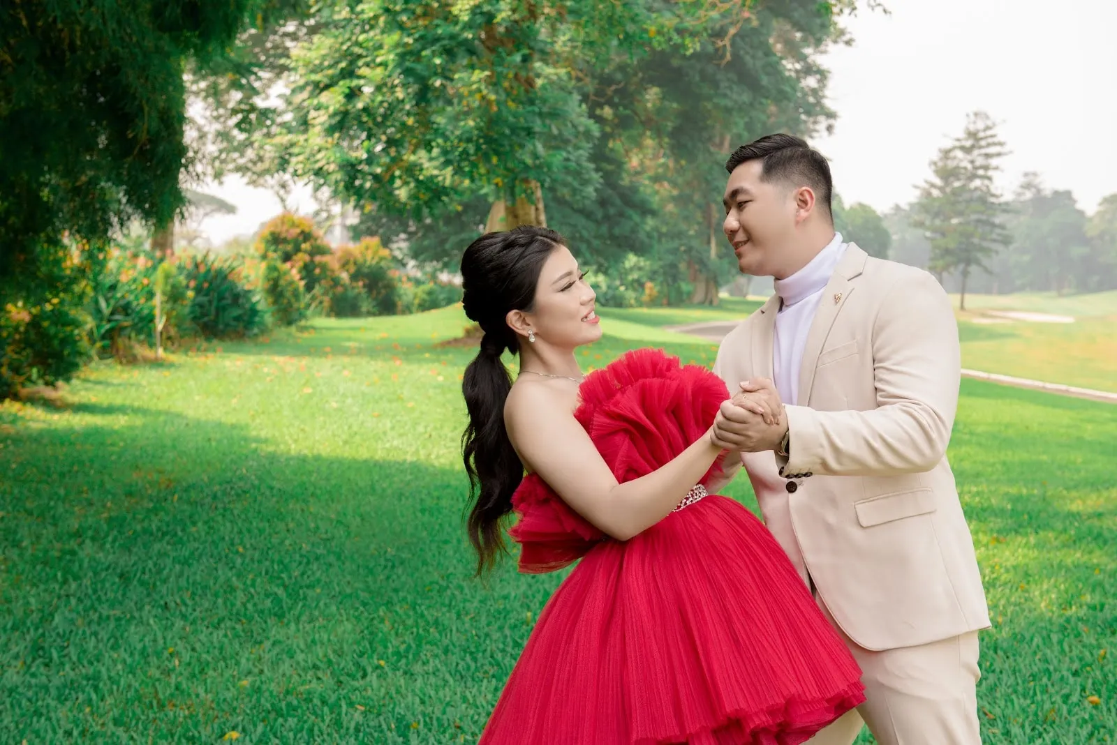 Pasangan prewedding tertawa di lapangan hijau