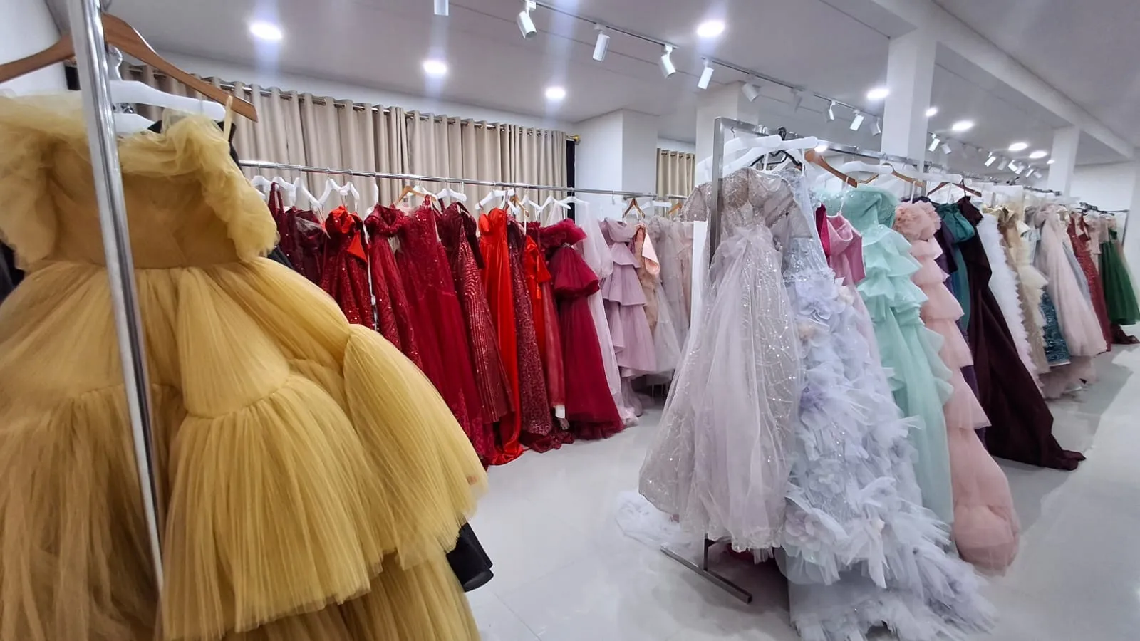 Rak gaun merah, kuning, dan pastel di butik